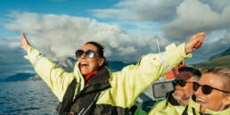Woman spreads arms open in joy during a RIB ride on the ocean.