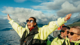 Woman spreads arms open in joy during a RIB ride on the ocean.