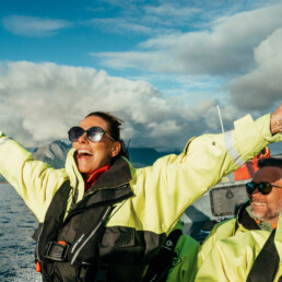 Woman spreads arms open in joy during a RIB ride on the ocean.